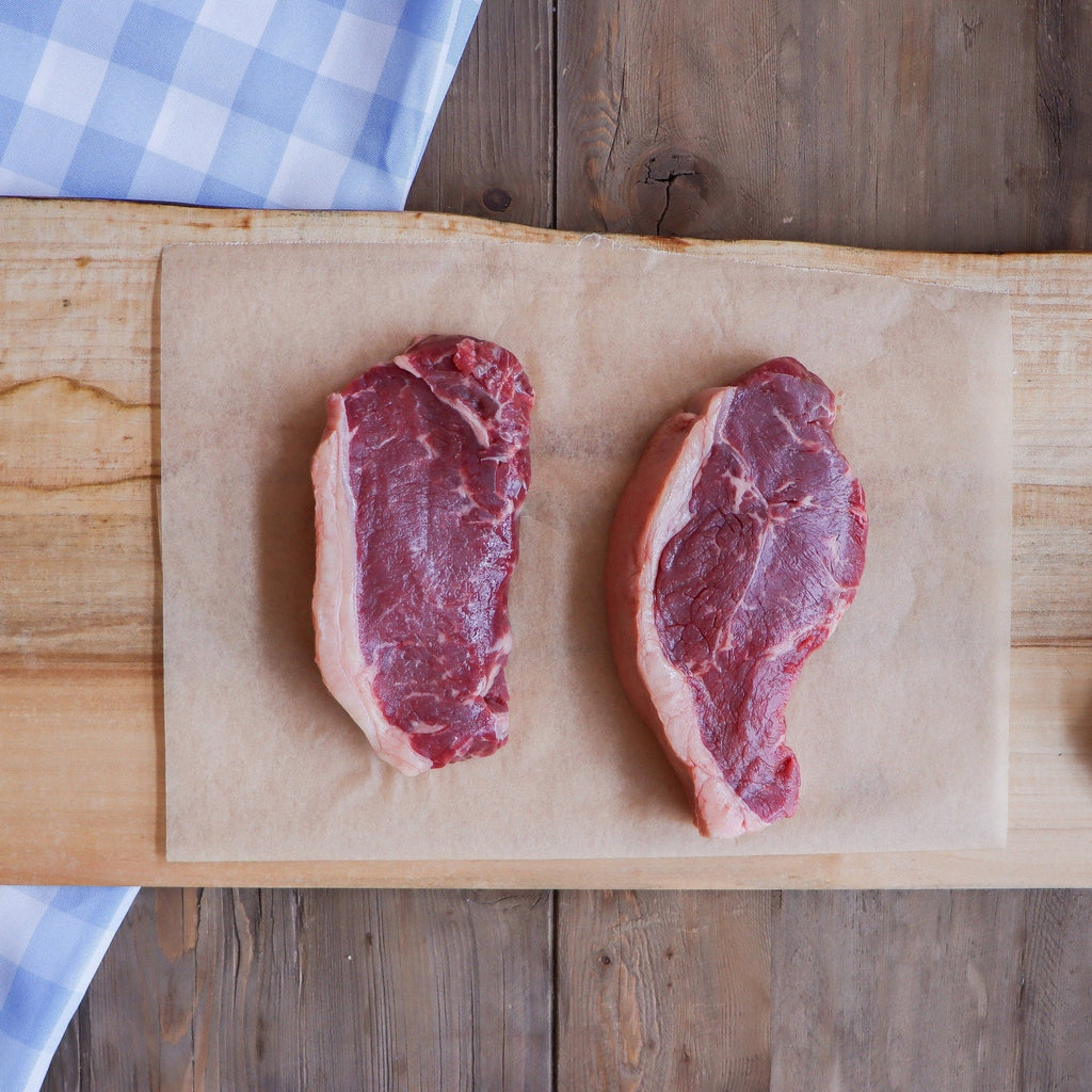image of two raw New York steaks on parchment paper