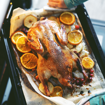 Image of a whole roasted duck on a pan with oranges and berries.