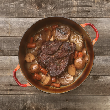 beef roast in a pot with vegetables sitting on a table