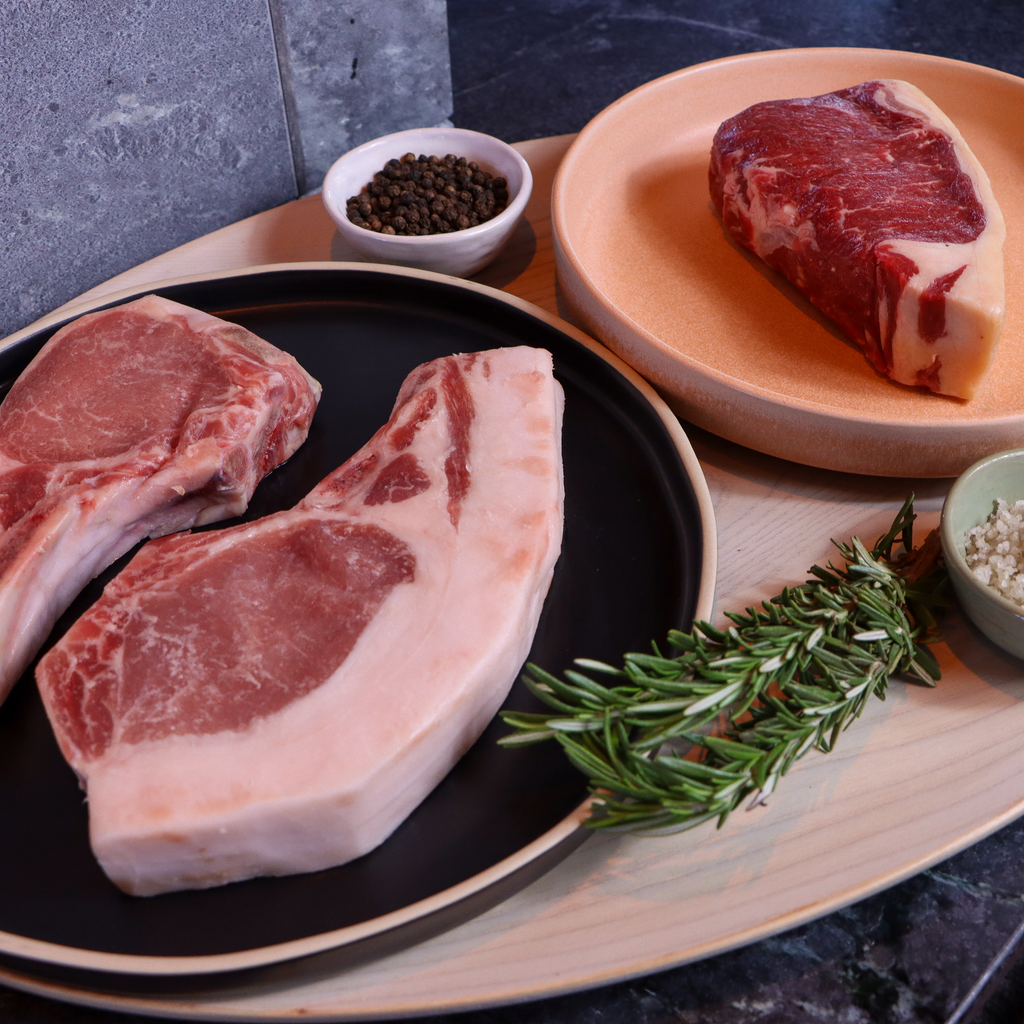 image of raw pork shoulder roasts and beef New York steak on two plates